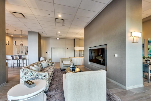 living room featuring hardwood / wood-style floors, a paneled ceiling, and a high ceiling