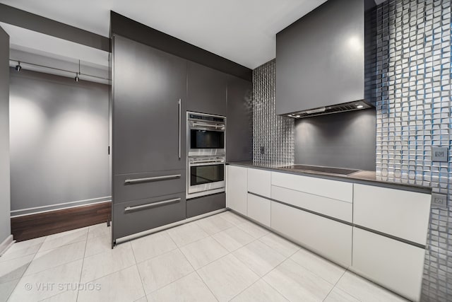 kitchen with wall chimney exhaust hood, stainless steel double oven, light hardwood / wood-style flooring, and black electric cooktop