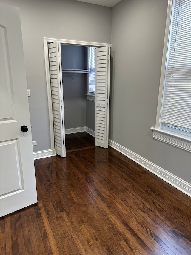 unfurnished bedroom featuring a closet and dark wood-type flooring