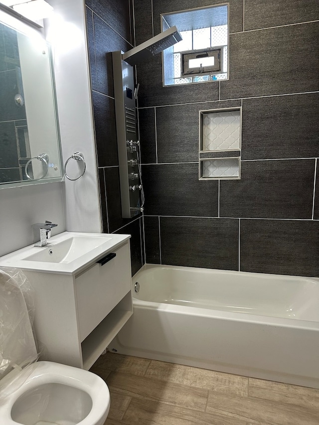 full bathroom featuring tiled shower / bath, vanity, and toilet