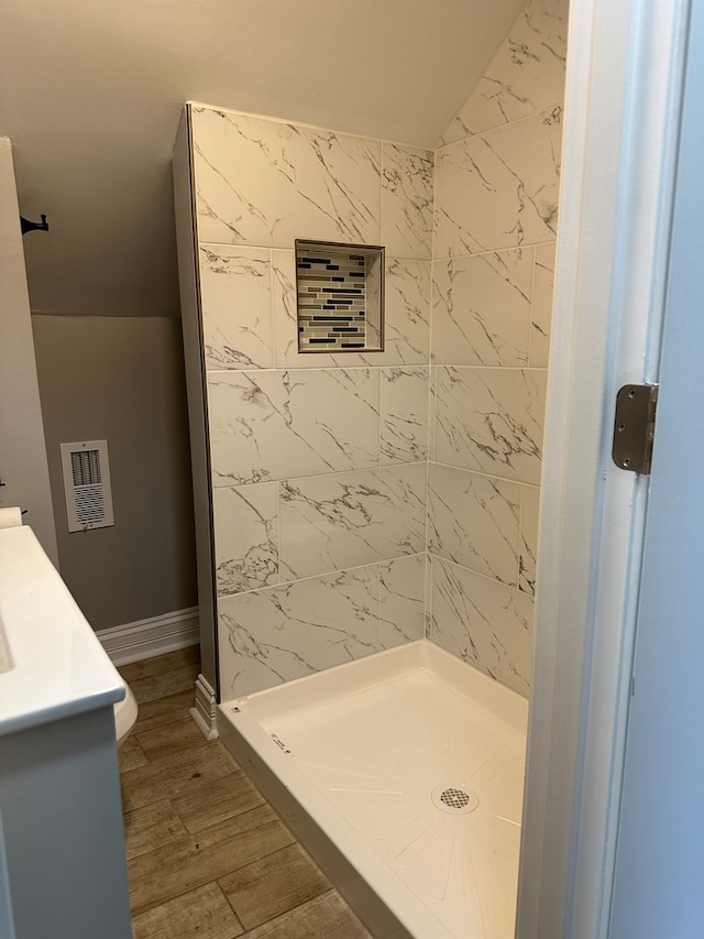 bathroom featuring hardwood / wood-style flooring and a tile shower