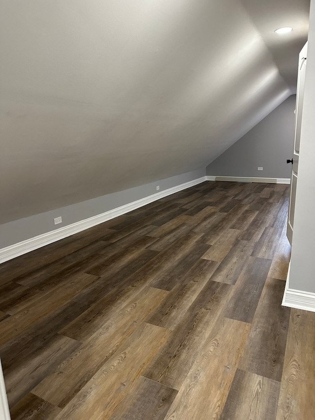 bonus room with dark hardwood / wood-style floors and vaulted ceiling