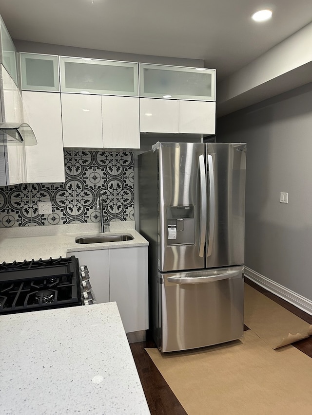 kitchen featuring white cabinetry, backsplash, sink, hardwood / wood-style flooring, and stainless steel fridge