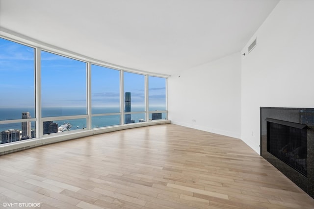 unfurnished living room with expansive windows, a water view, and light wood-type flooring