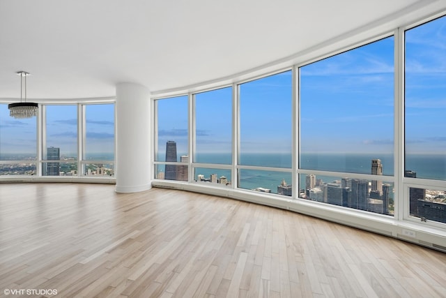 interior space featuring a notable chandelier, expansive windows, a water view, and light hardwood / wood-style flooring