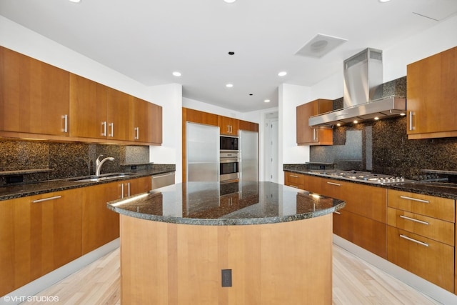 kitchen with light wood-type flooring, ventilation hood, stainless steel appliances, sink, and a kitchen island