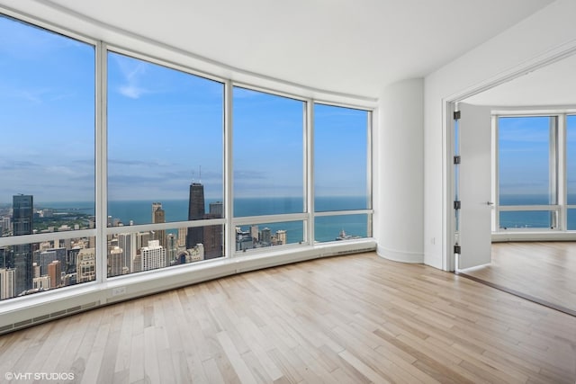 unfurnished room featuring light wood-type flooring and a water view