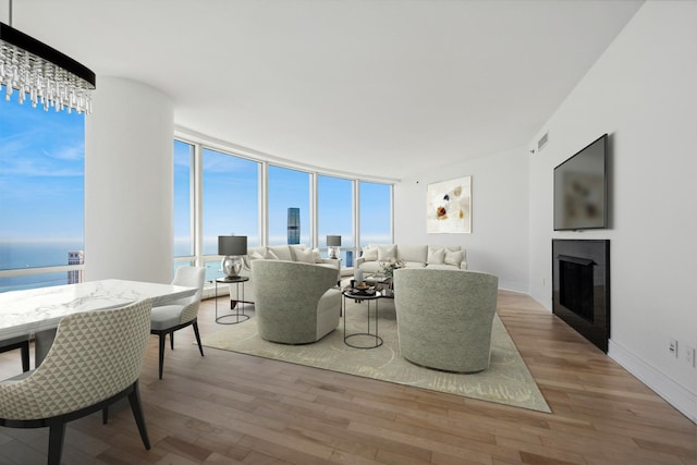 living room featuring expansive windows, a water view, and light wood-type flooring