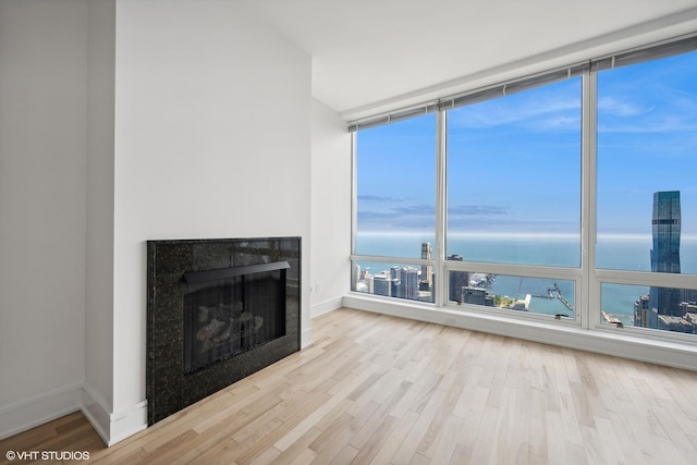 unfurnished living room with expansive windows, a water view, and light hardwood / wood-style flooring