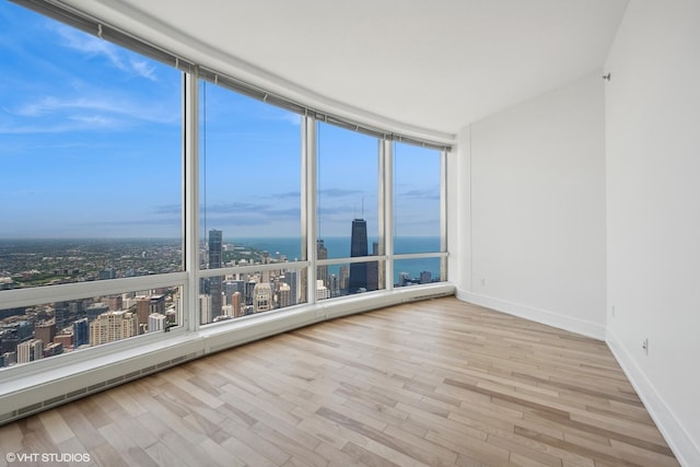 unfurnished room with a water view, a wall of windows, and light hardwood / wood-style flooring