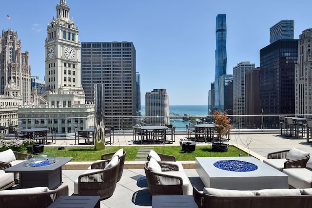 view of patio with a water view and an outdoor living space with a fire pit