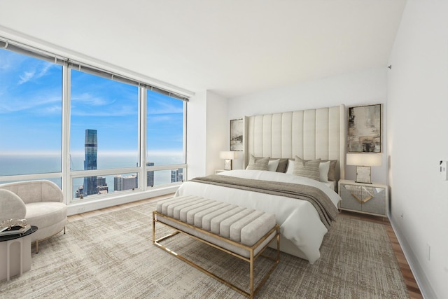 bedroom with hardwood / wood-style flooring, expansive windows, and a water view