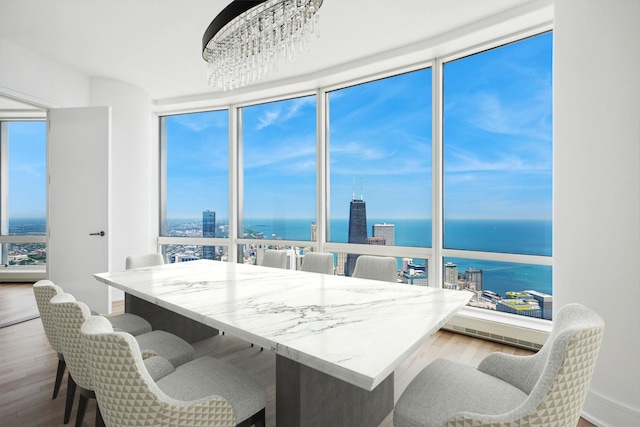 dining area with hardwood / wood-style flooring, a healthy amount of sunlight, a water view, and a chandelier