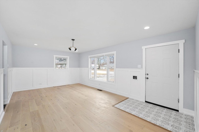 foyer entrance featuring light wood-style floors, recessed lighting, visible vents, and wainscoting