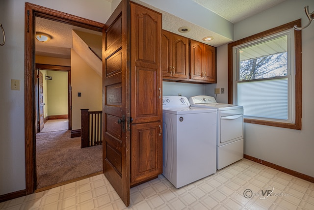 laundry area with washer and clothes dryer, light colored carpet, cabinets, and a textured ceiling