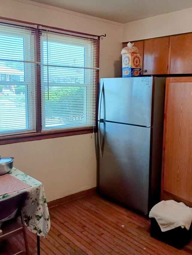 kitchen with light hardwood / wood-style floors, crown molding, and stainless steel refrigerator