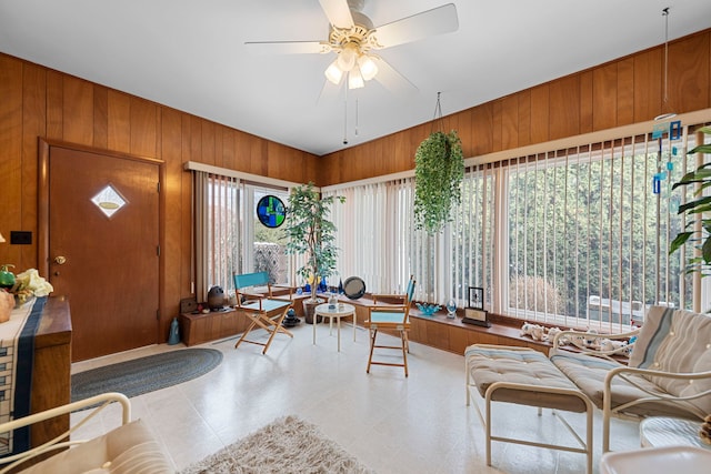 interior space with ceiling fan and wood walls