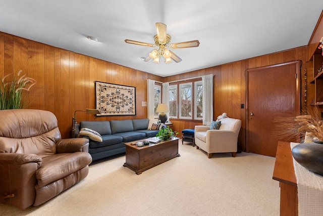 living room featuring wooden walls, light carpet, and ceiling fan