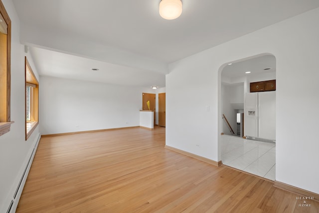 tiled empty room featuring baseboard heating