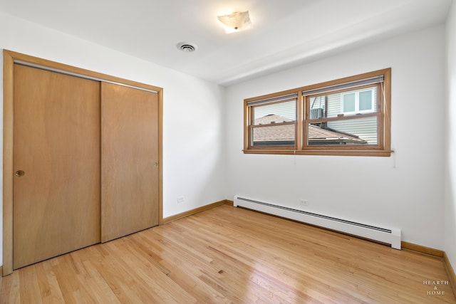 unfurnished bedroom featuring a closet, a baseboard radiator, and light wood-type flooring