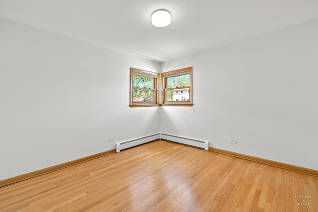 empty room featuring a baseboard radiator and light wood-type flooring