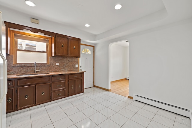 kitchen featuring backsplash, a baseboard radiator, sink, and light tile flooring