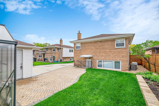 rear view of property with a patio area, a yard, and central AC