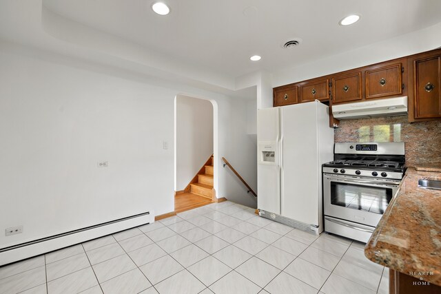 kitchen with white fridge with ice dispenser, gas stove, light tile floors, tasteful backsplash, and a baseboard radiator