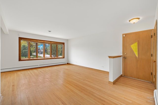 unfurnished room featuring light wood-type flooring and a baseboard heating unit