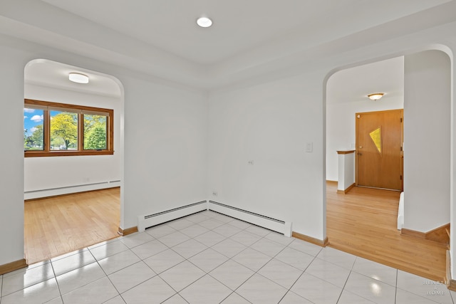 tiled spare room with a baseboard heating unit