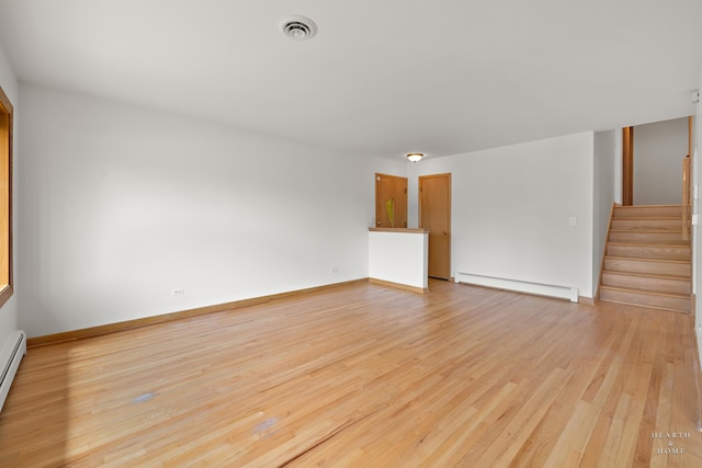 empty room with a baseboard heating unit and light hardwood / wood-style flooring