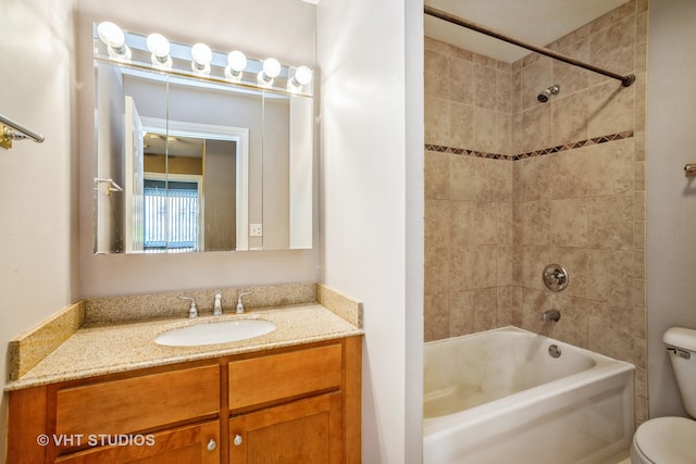 full bathroom with tiled shower / bath, vanity, and toilet