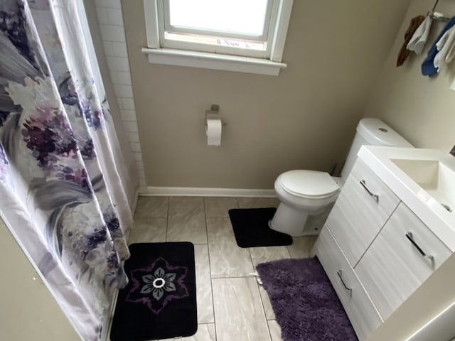 bathroom featuring tile flooring, vanity, and toilet