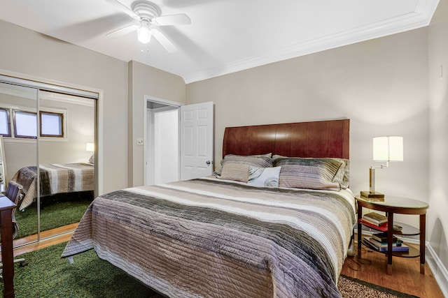 bedroom with ornamental molding, a closet, wood-type flooring, and ceiling fan