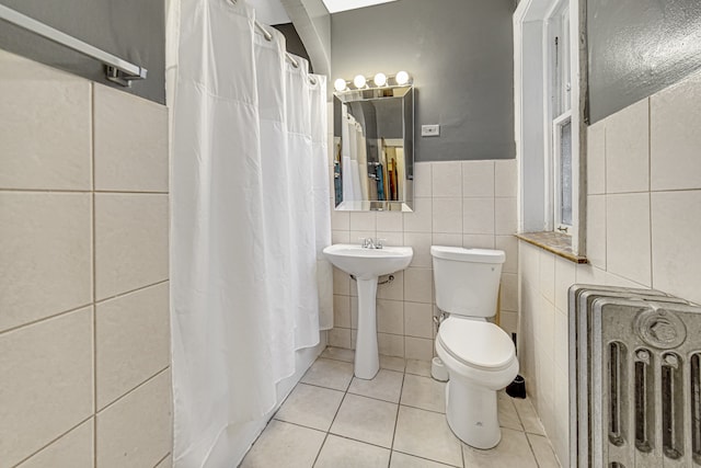 bathroom featuring radiator heating unit, toilet, tile flooring, and tile walls