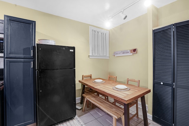 kitchen with light tile floors, track lighting, and black refrigerator