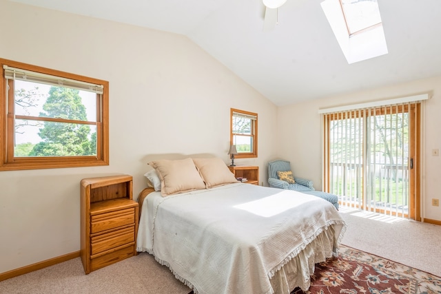 carpeted bedroom with multiple windows, ceiling fan, and lofted ceiling with skylight