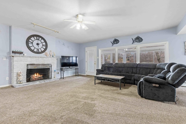 carpeted living room with a fireplace, rail lighting, and ceiling fan