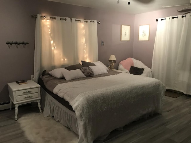 bedroom featuring hardwood / wood-style flooring, ceiling fan, and baseboard heating