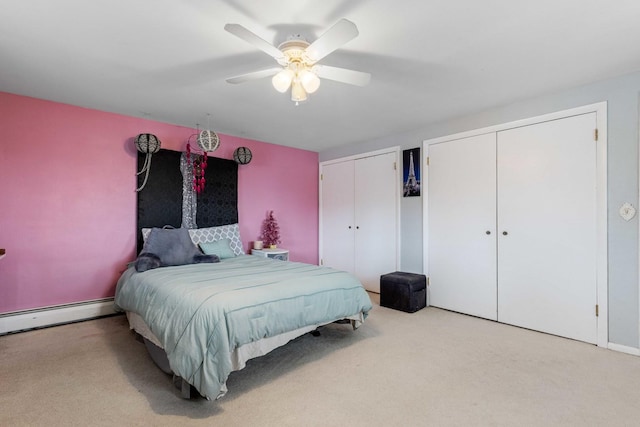 bedroom with baseboard heating, two closets, ceiling fan, and light carpet