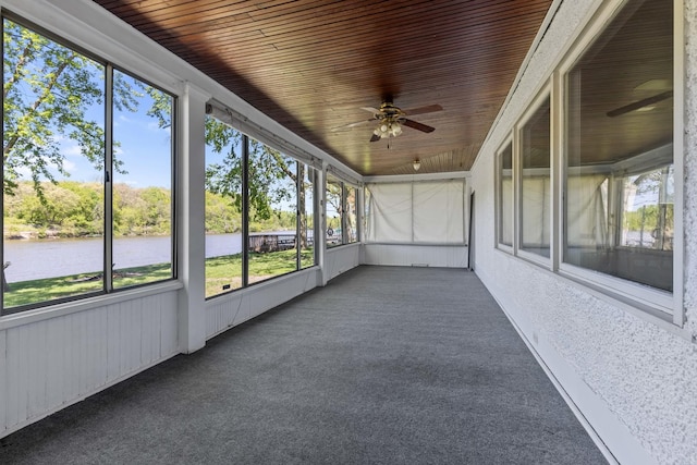 unfurnished sunroom featuring ceiling fan, wood ceiling, and a water view