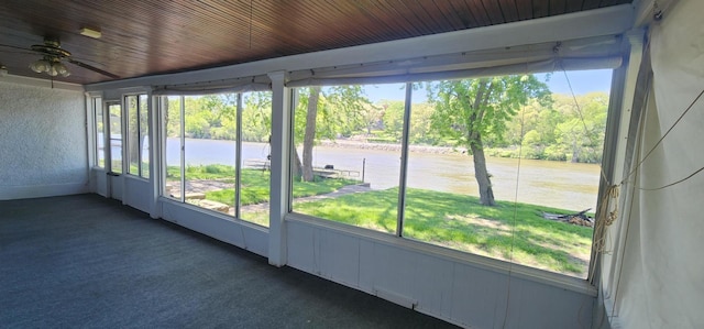 unfurnished sunroom featuring ceiling fan, wood ceiling, and a water view