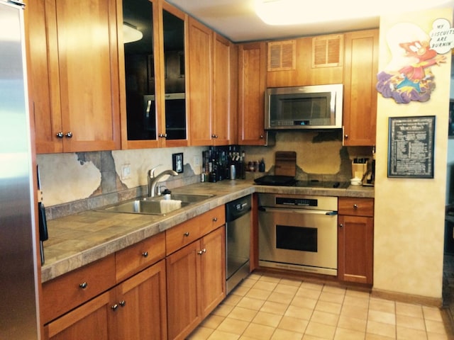 kitchen featuring backsplash, sink, light tile patterned floors, and stainless steel appliances