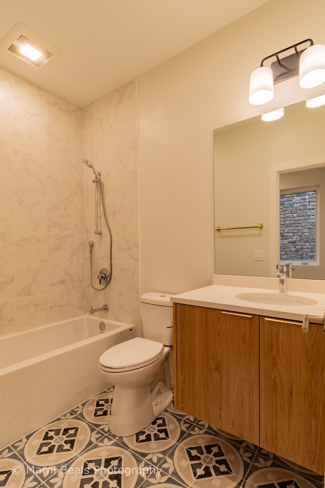 full bathroom with tile flooring, tiled shower / bath, vanity, and toilet