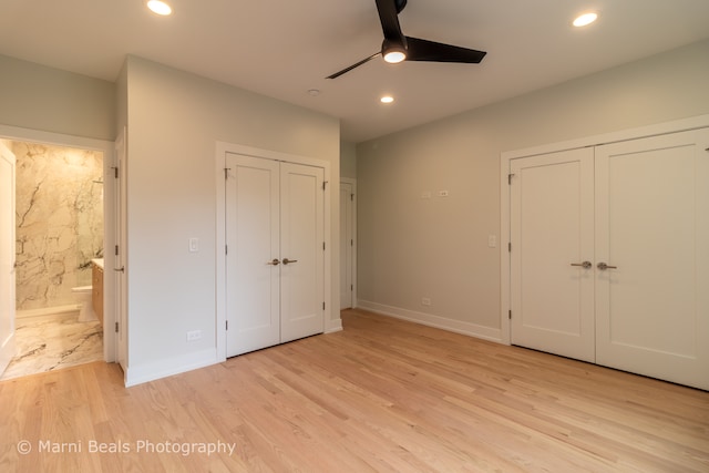 unfurnished bedroom with light hardwood / wood-style floors, ceiling fan, two closets, and ensuite bath