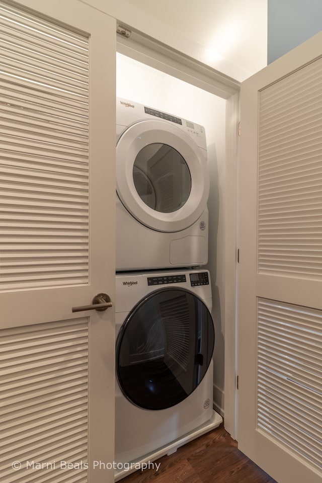 washroom featuring dark wood-type flooring and stacked washer and clothes dryer