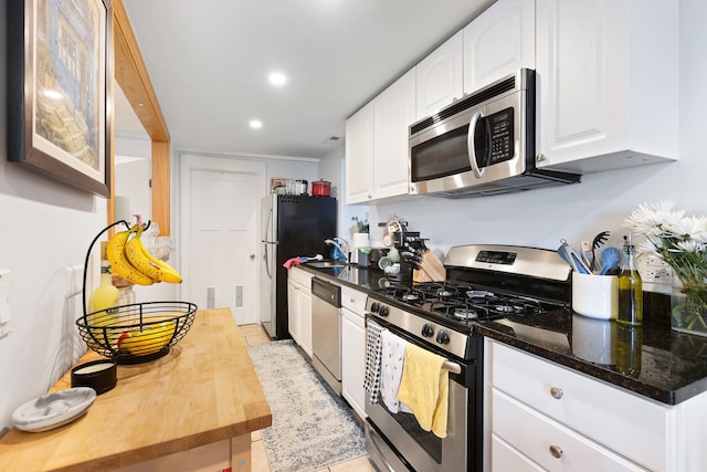 kitchen with dark stone counters, stainless steel appliances, white cabinets, and sink