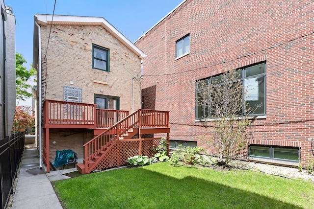 rear view of house featuring a wooden deck and a lawn