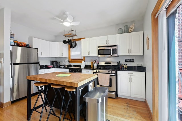 kitchen featuring ceiling fan, a center island, light wood-type flooring, stainless steel appliances, and butcher block counters