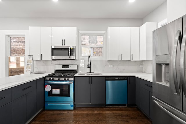 kitchen with appliances with stainless steel finishes, a wealth of natural light, dark hardwood / wood-style flooring, and white cabinets